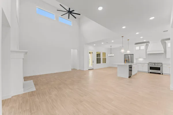 a view of an empty room with kitchen and a window
