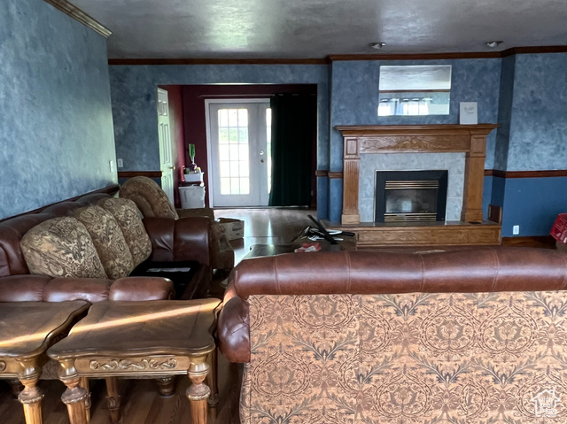 108 South Road Montpelier, ID 83254 - Photo 6 of 36 Living area with a tiled fireplace, ornamental molding, wood finished floors, and a textured ceiling