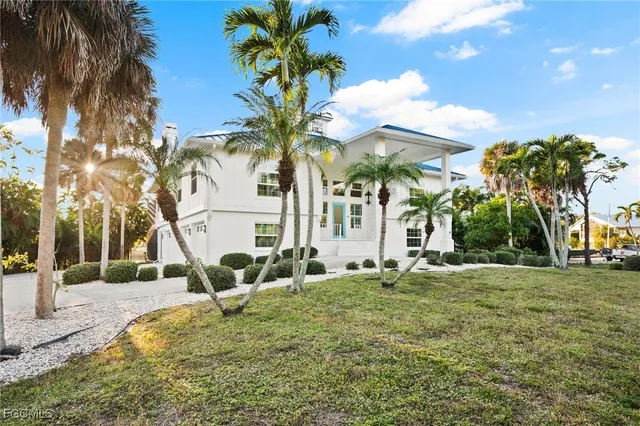 a view of a house with a yard and palm trees