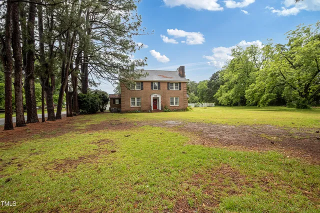 a front view of house with yard and trees in the background