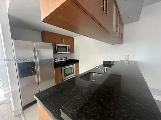 a kitchen with stainless steel appliances granite countertop a sink and a stove