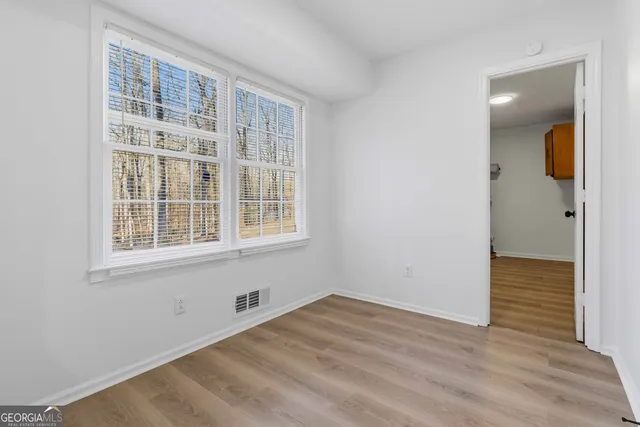 a view of an empty room with wooden floor and a window