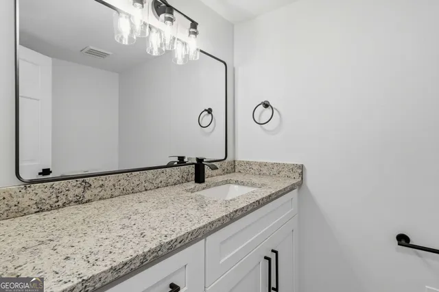 a bathroom with a granite countertop sink and a mirror