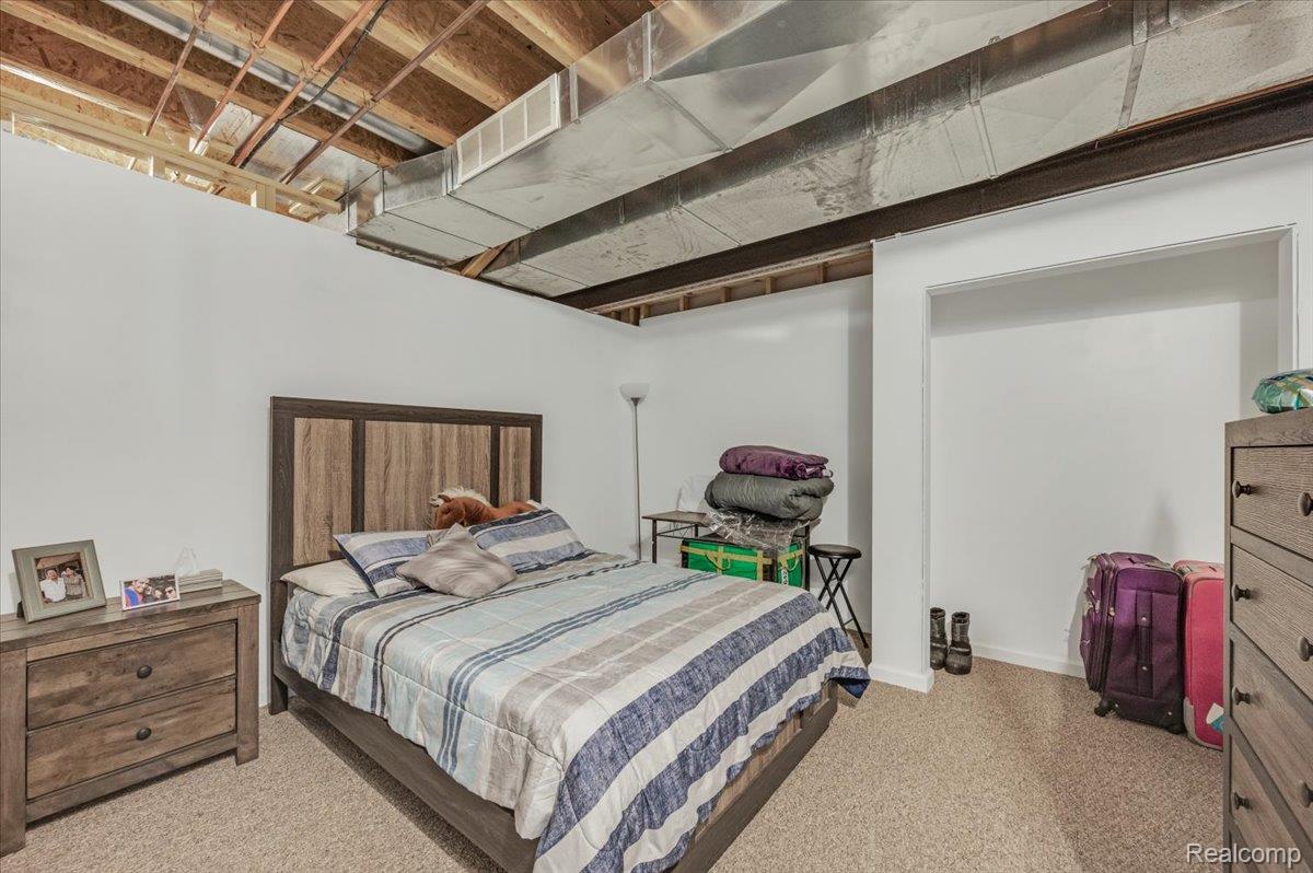 2551 Marathon Road Lapeer, MI 48446 - Photo 31 of 33 Carpeted room featuring white painted walls and an open ceiling with exposed wood joists and metal ductwork