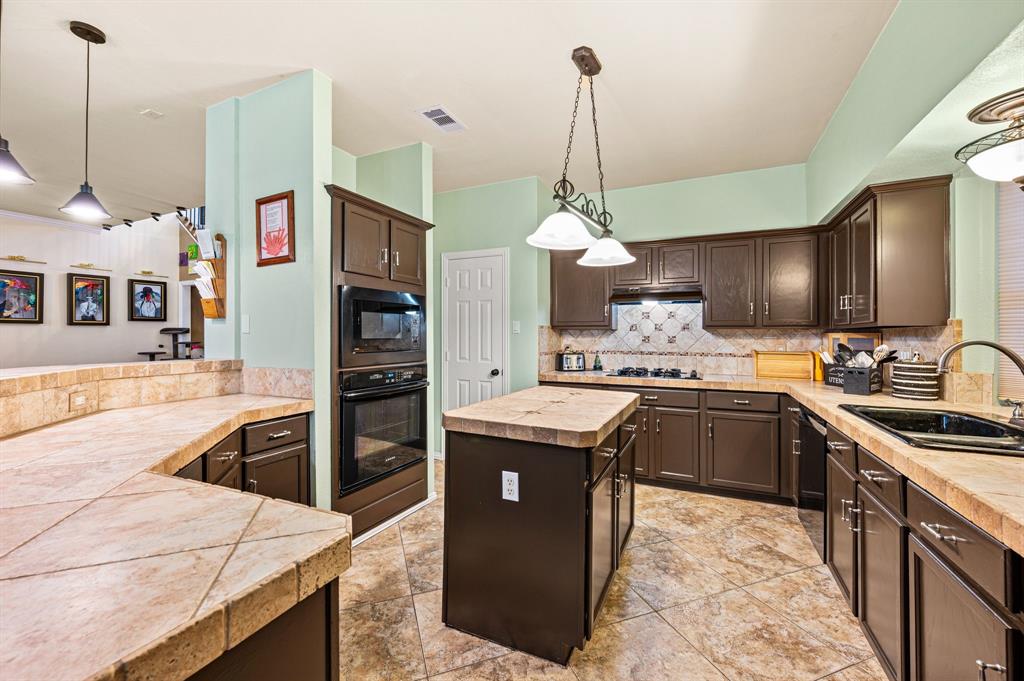 4008 Falcon Ridge Drive Haltom City, TX 76137 - Photo 12 of 32 a kitchen with stainless steel appliances granite countertop a sink a stove and a wooden floors