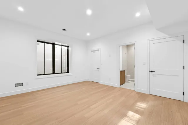 a view of an empty room with window and wooden floor