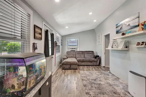 a living room with stainless steel appliances furniture a fireplace and a flat screen tv