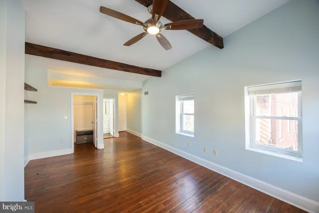 a view of an empty room with window and wooden floor