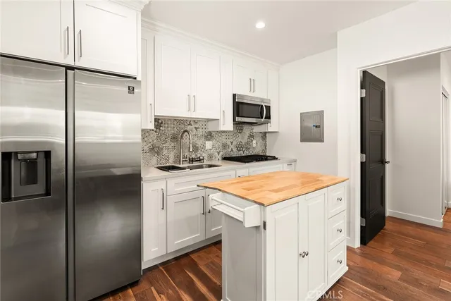 a kitchen with stainless steel appliances granite countertop a refrigerator a stove and a sink with wooden floor