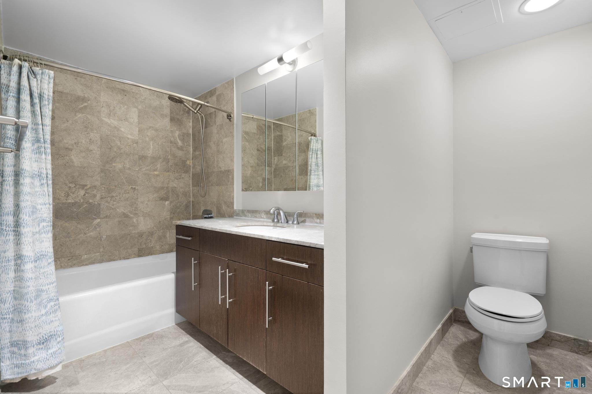 25 Forest Street, Unit 15E Stamford, CT 06901 - Photo 20 of 40 a bathroom with a granite countertop sink a toilet and bathtub