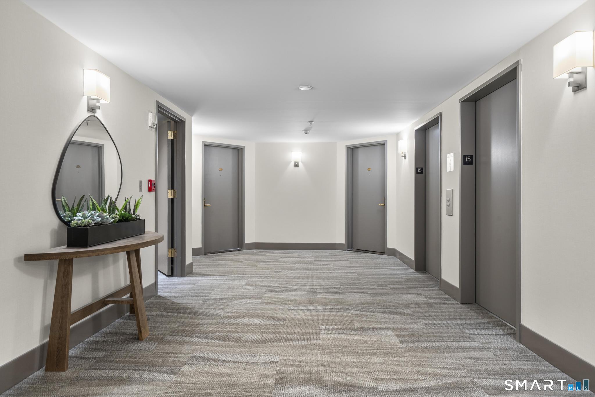 25 Forest Street, Unit 15E Stamford, CT 06901 - Photo 25 of 40 a view of a hallway with wooden floor and a potted plant