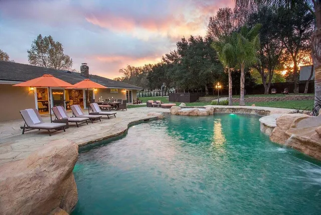 a backyard of a house with table and chairs under an umbrella