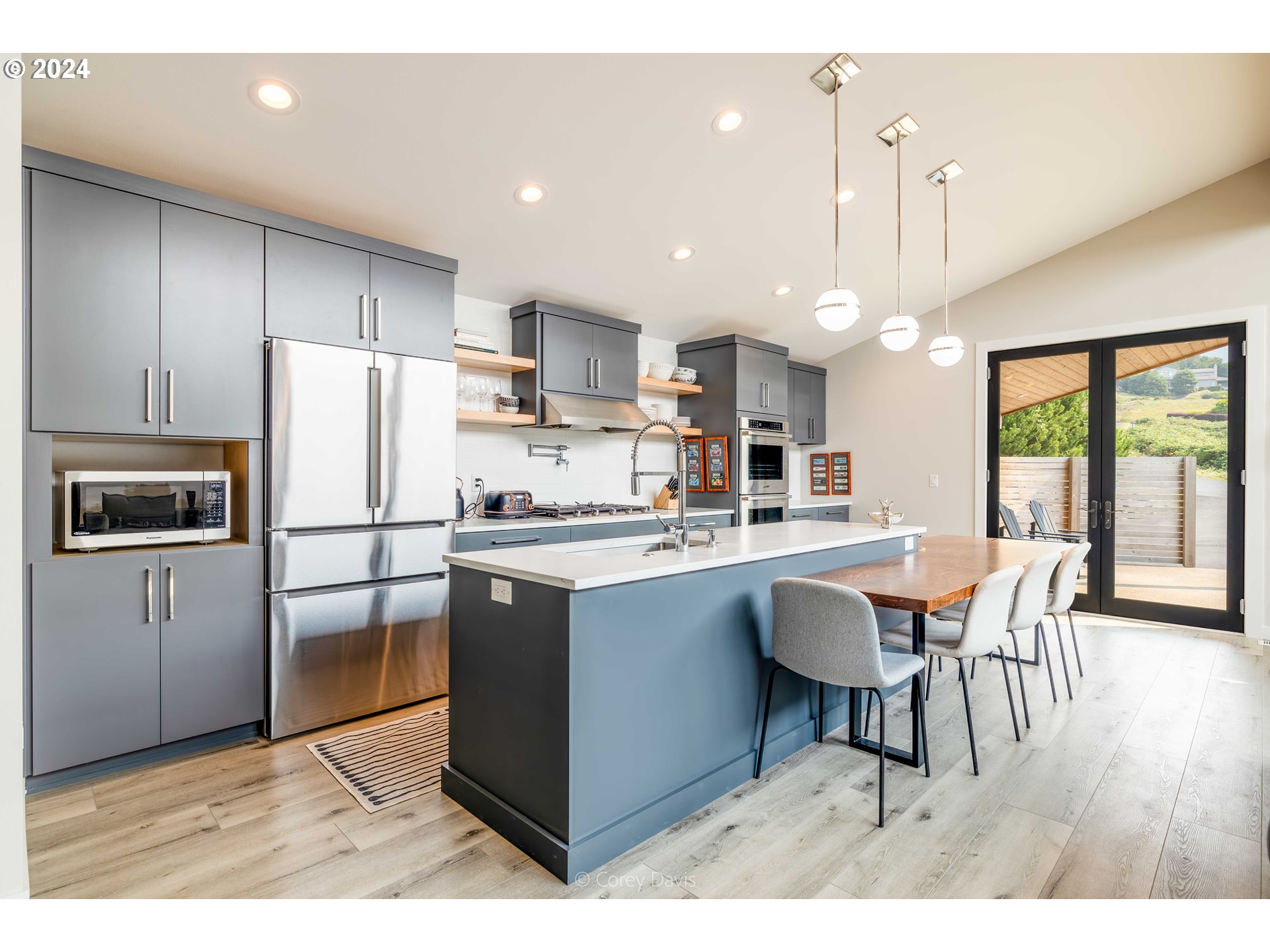 8760 Mariners Nehalem, OR 97131 - Photo 15 of 40 a kitchen with stainless steel appliances granite countertop a refrigerator a stove a sink dishwasher a dining table and chairs with wooden floor