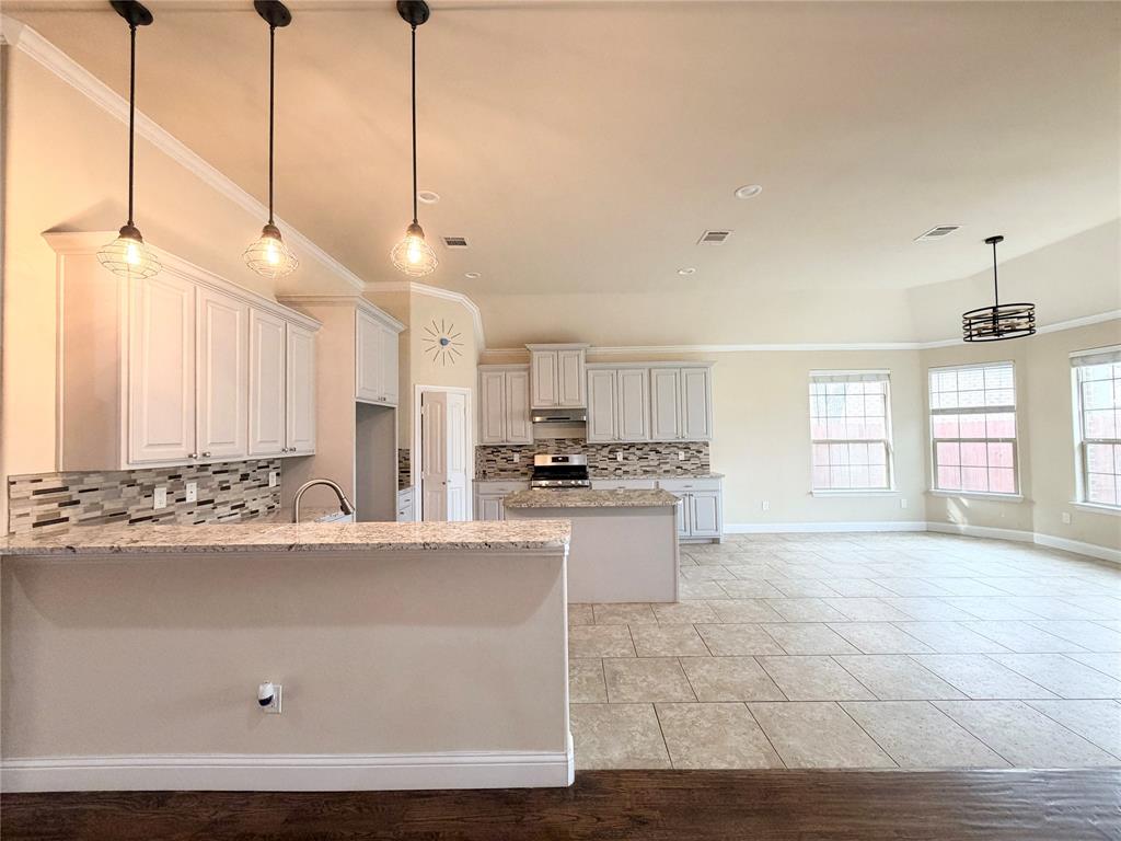 501 Elwood Road Irving, TX 75061 - Photo 6 of 30 a large white kitchen with kitchen island a stove a sink dishwasher and a refrigerator with wooden floor