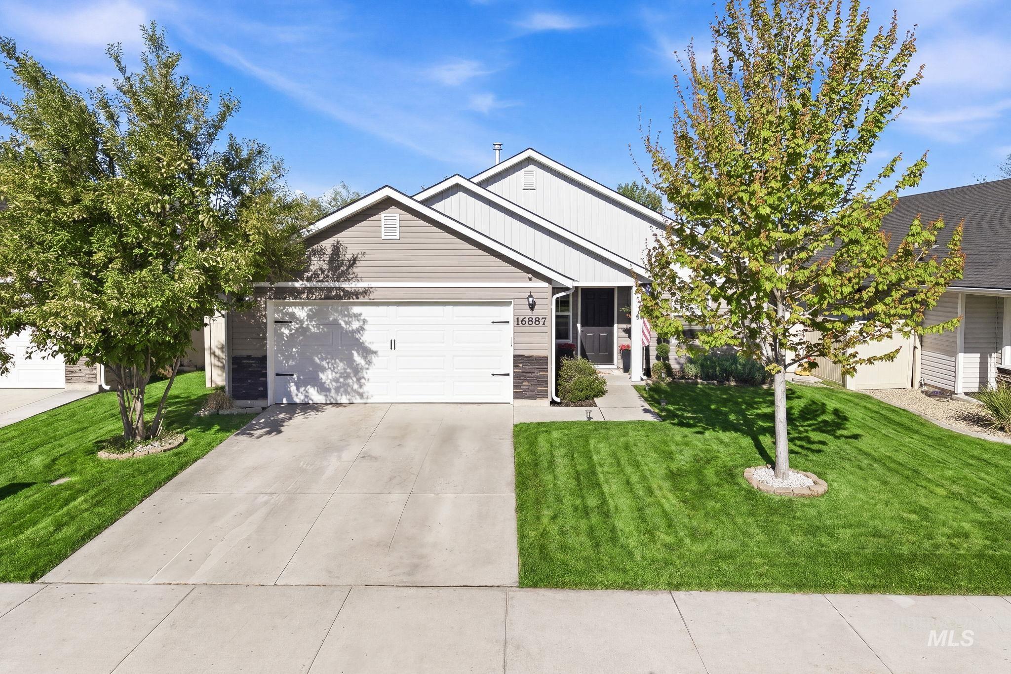 Contemporary exterior featuring horizontal siding in two tones, stone accents, a two-car garage, and a concrete driveway