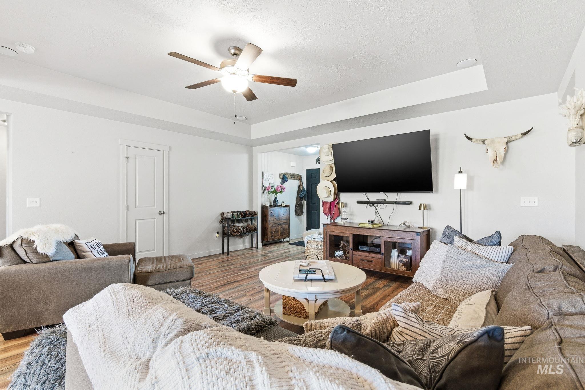 16887 Bethany Avenue Caldwell, ID 83607 - Photo 11 of 50 Spacious living area featuring wood-finish flooring, a ceiling fan, and a tray ceiling