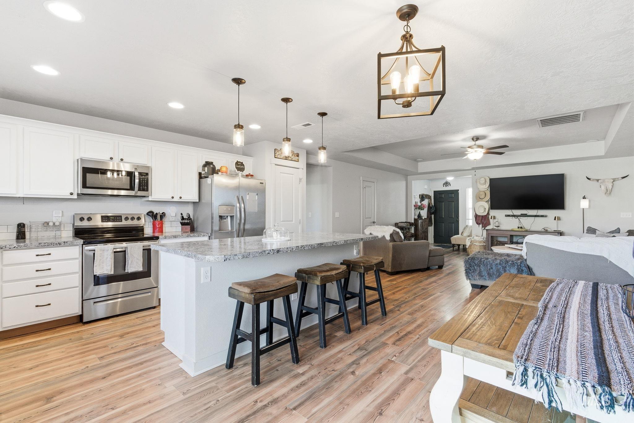 16887 Bethany Avenue Caldwell, ID 83607 - Photo 16 of 50 Open-concept kitchen and living area featuring wood-finish flooring, recessed lighting, and a kitchen island with seating