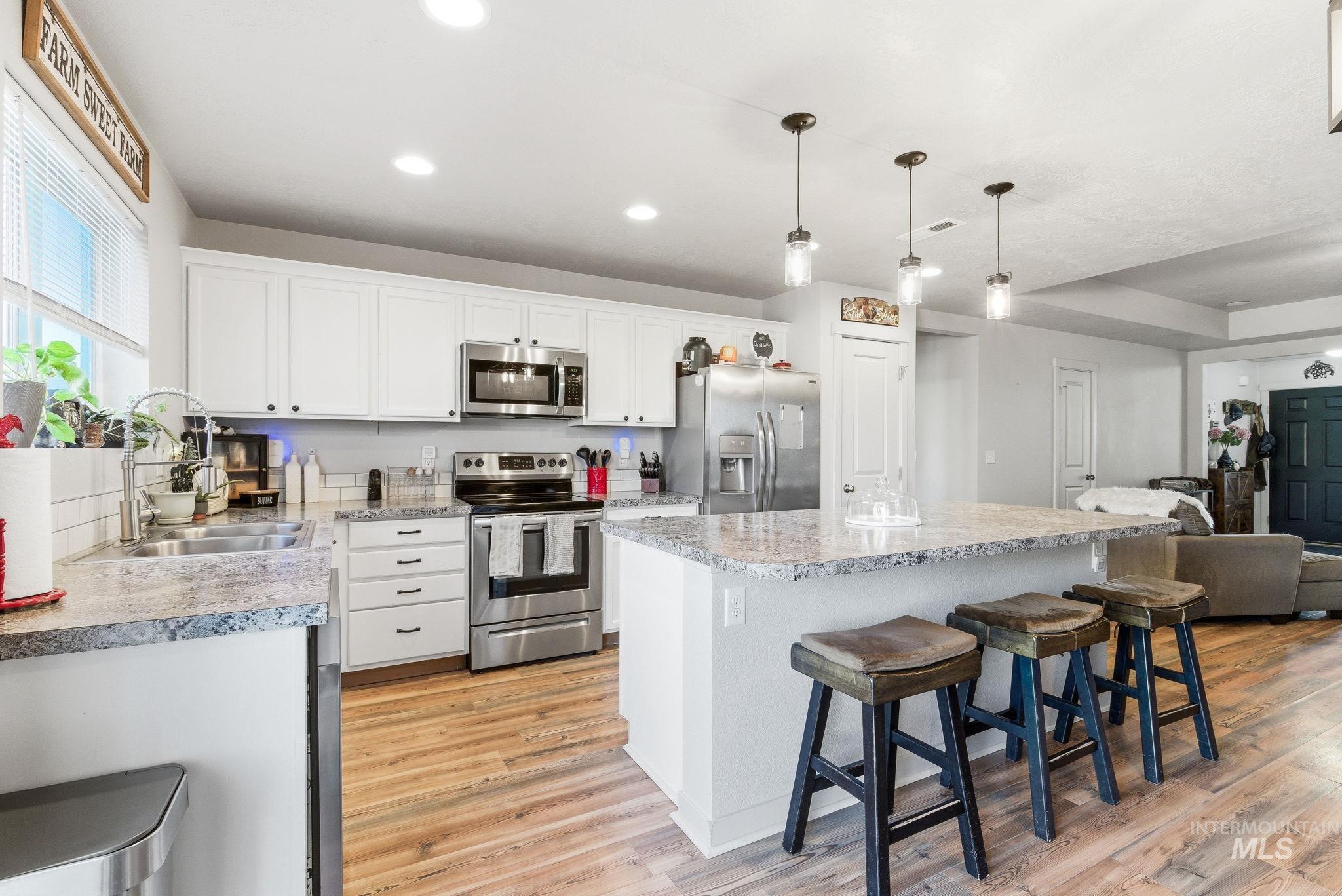 16887 Bethany Avenue Caldwell, ID 83607 - Photo 17 of 50 Kitchen featuring granite-style countertops, white cabinetry, and stainless steel appliances