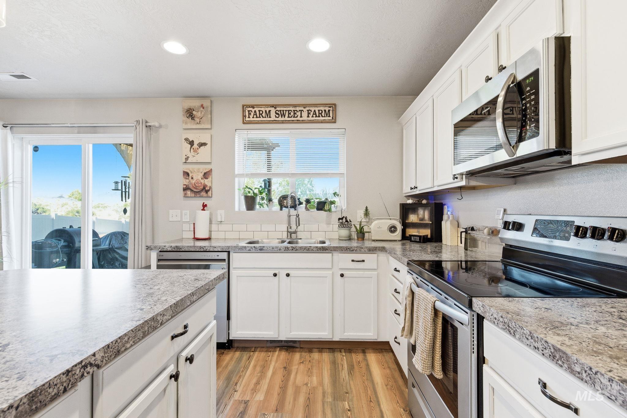 16887 Bethany Avenue Caldwell, ID 83607 - Photo 20 of 50 Contemporary kitchen featuring white cabinetry, light countertops, wood-finish flooring, stainless steel appliances, and a subway tile backsplash