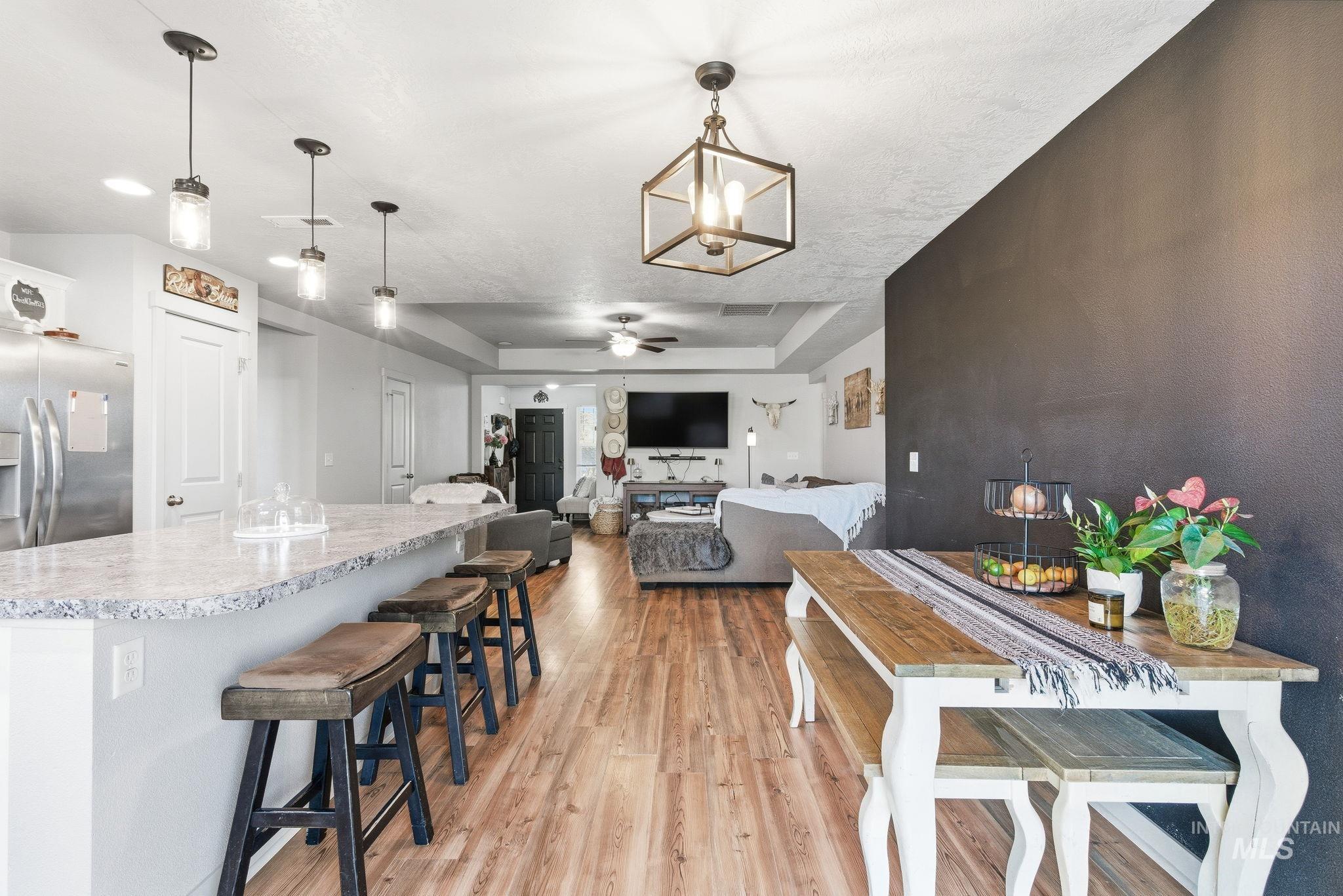 16887 Bethany Avenue Caldwell, ID 83607 - Photo 22 of 50 Open-concept living space featuring wood-finish flooring, a kitchen island with seating, pendant lighting, a ceiling fan, and a neutral color palette