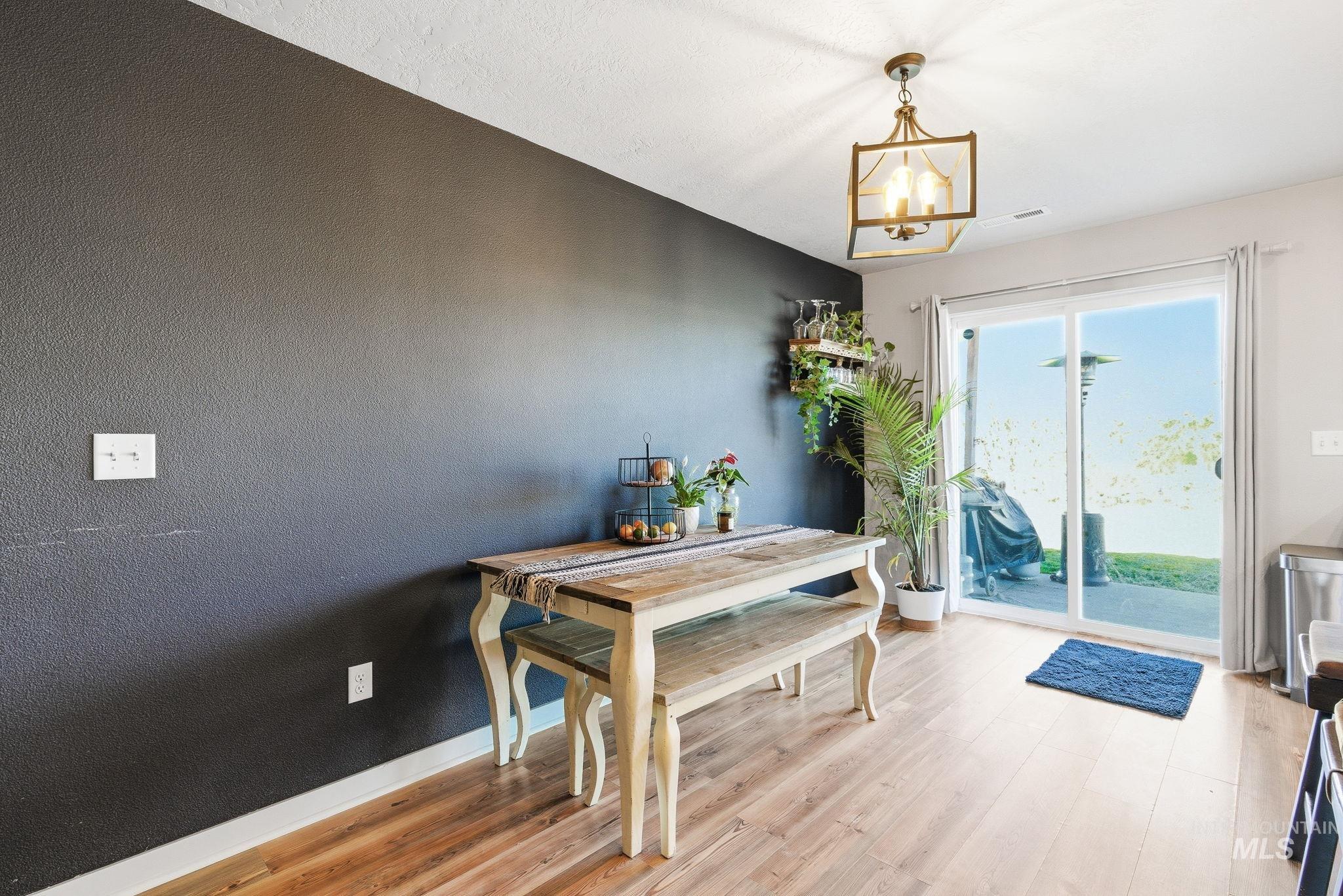 16887 Bethany Avenue Caldwell, ID 83607 - Photo 23 of 50 Dining area featuring wood-finish flooring, a contemporary pendant light fixture, a dark accent wall, and sliding glass doors leading to the exterior