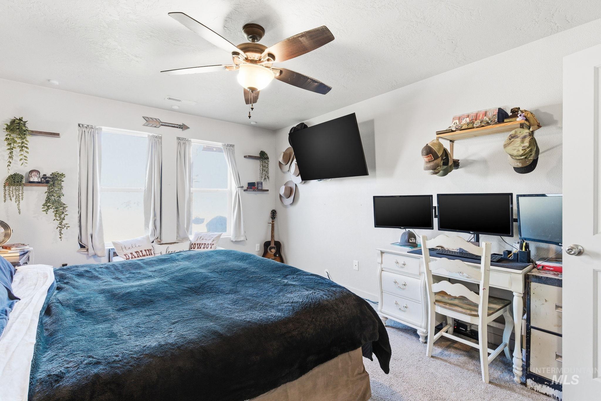 16887 Bethany Avenue Caldwell, ID 83607 - Photo 25 of 50 Carpeted room featuring a ceiling fan with integrated lighting, multiple windows with neutral drapery, and built-in wall shelving