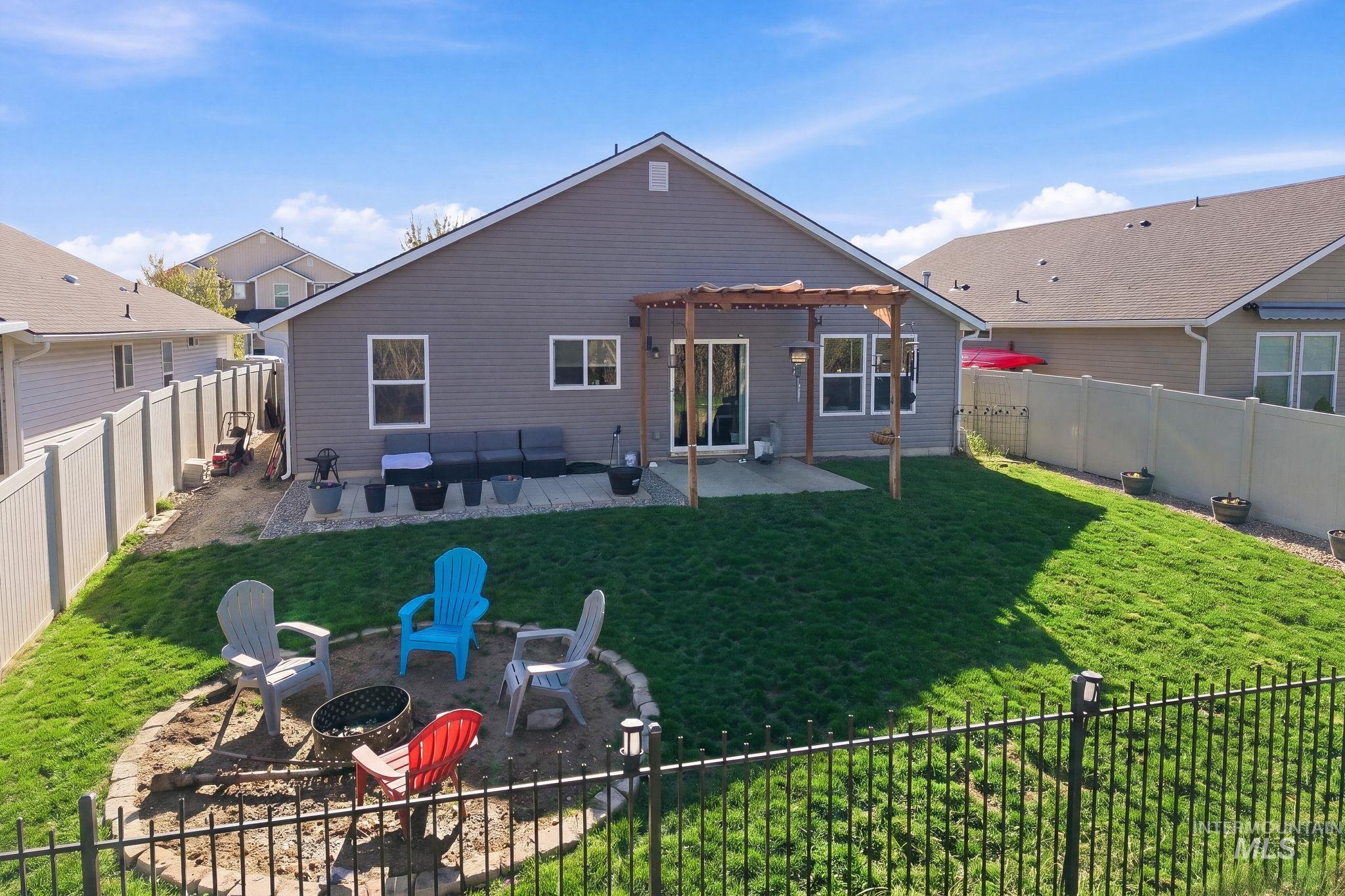16887 Bethany Avenue Caldwell, ID 83607 - Photo 40 of 50 Spacious backyard featuring a built-in fire pit, a concrete patio, a wooden pergola, and privacy fencing