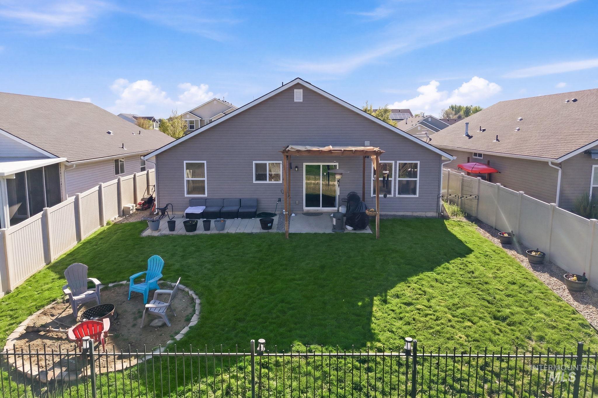 16887 Bethany Avenue Caldwell, ID 83607 - Photo 42 of 50 Expansive backyard featuring a manicured lawn, a concrete patio with a wooden pergola, and a built-in fire pit area