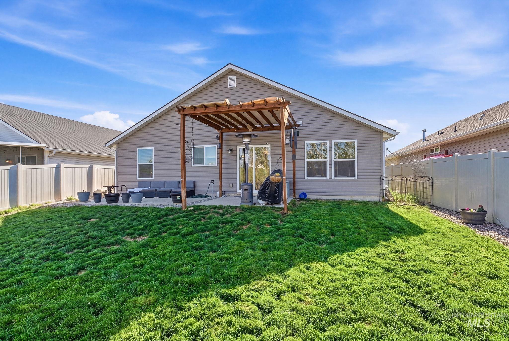 16887 Bethany Avenue Caldwell, ID 83607 - Photo 43 of 50 Spacious backyard with a grey vinyl-sided exterior and a wooden pergola covering a patio area
