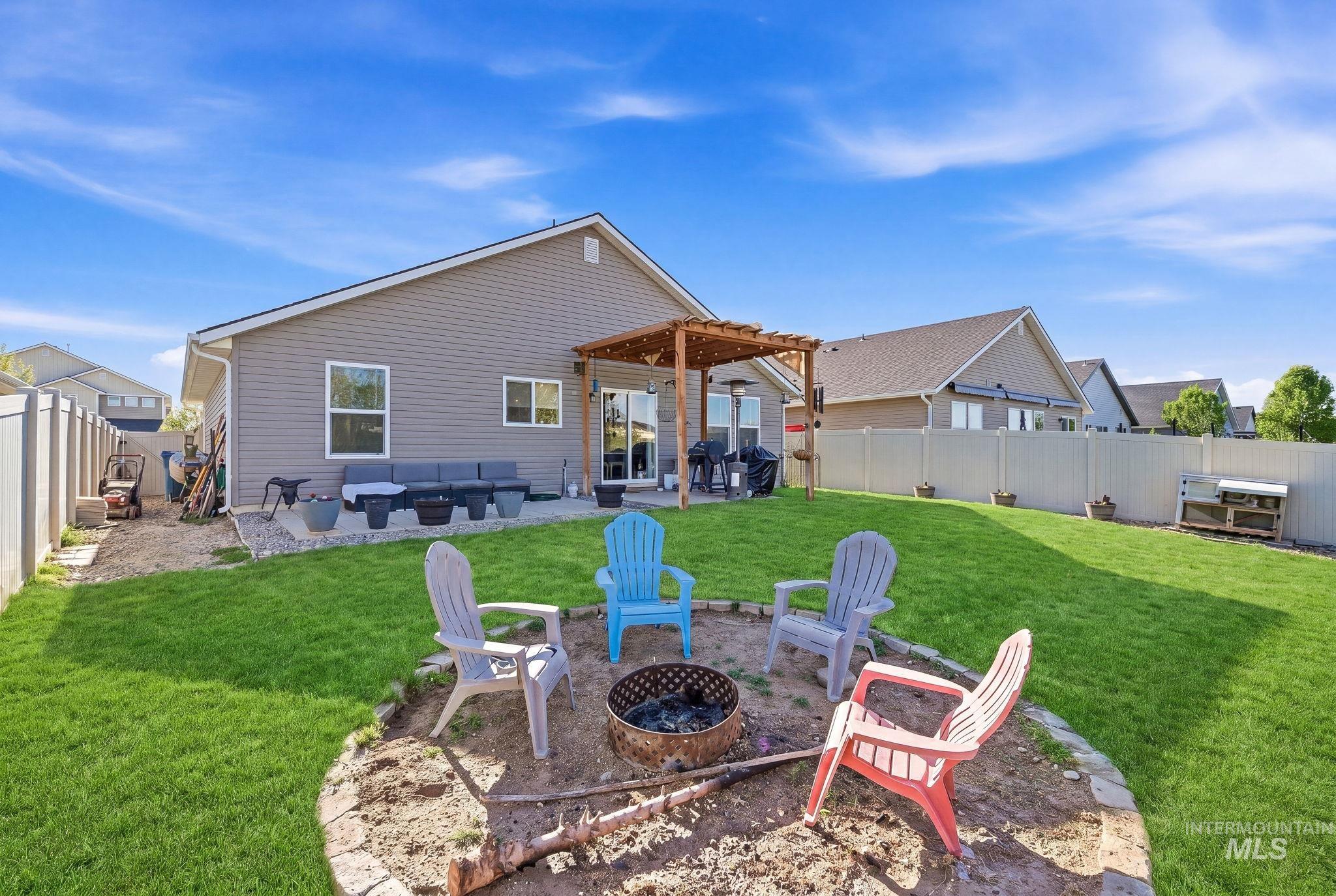 16887 Bethany Avenue Caldwell, ID 83607 - Photo 45 of 50 Expansive backyard featuring a manicured lawn, a built-in fire pit with stone surround, and a concrete patio