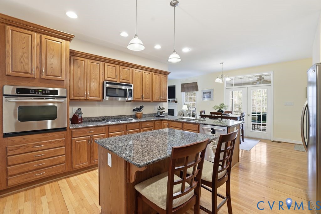 13630 River Road Chesterfield, VA 23838 - Photo 22 of 57 a kitchen with stainless steel appliances granite countertop a stove top oven a refrigerator a sink a dining table and chairs with wooden floor