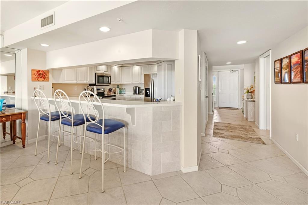 21 Bluebill Avenue, Unit 403B Naples, FL 34108 - Photo 12 of 37 a kitchen with stainless steel appliances kitchen island granite countertop a refrigerator and cabinets