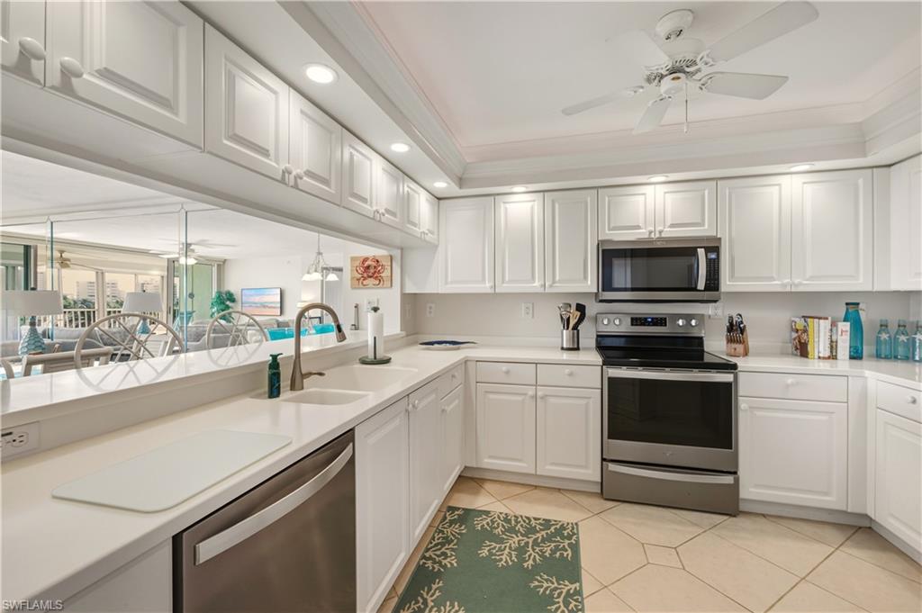21 Bluebill Avenue, Unit 403B Naples, FL 34108 - Photo 13 of 37 a kitchen with a sink stainless steel appliances and white cabinets