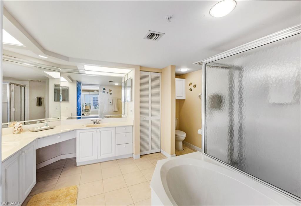 21 Bluebill Avenue, Unit 403B Naples, FL 34108 - Photo 19 of 37 a large bathroom with a mirror a double vanity sink and a shower