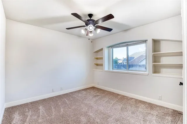 an empty room with window and ceiling fan