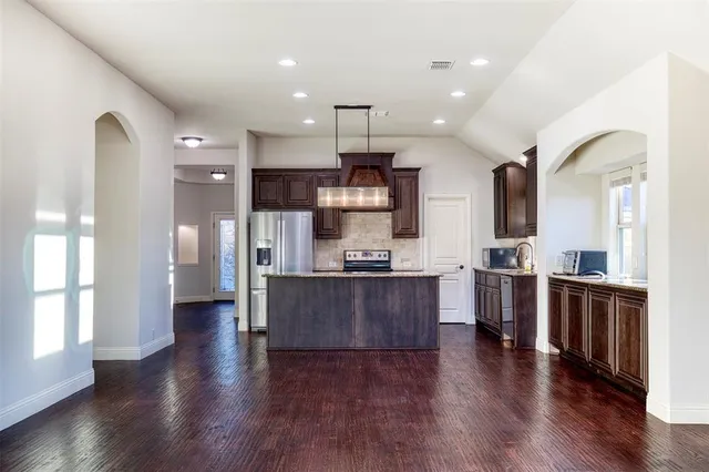 a large kitchen with stainless steel appliances kitchen island granite countertop wooden floors and a sink