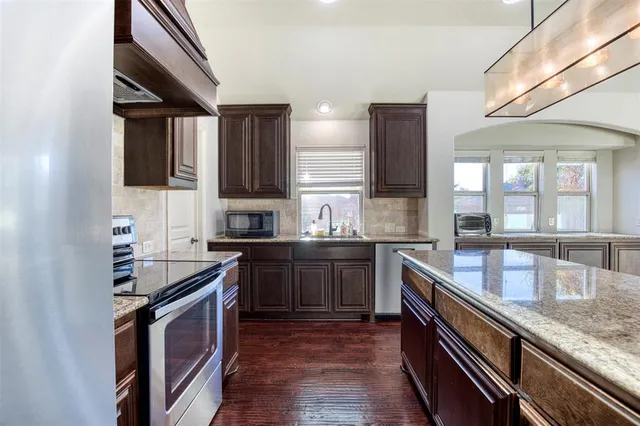 a kitchen with stainless steel appliances granite countertop a sink stove and refrigerator