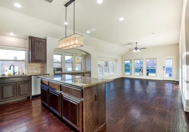a kitchen with stainless steel appliances granite countertop a stove top oven a sink with wooden floors