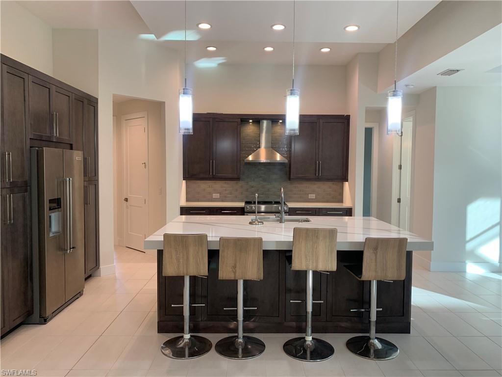 214 Legacy Court Naples, FL 34110 - Photo 14 of 49 a kitchen with stainless steel appliances kitchen island granite countertop a table and chairs in it