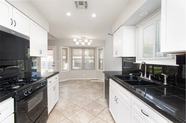 a kitchen with granite countertop a stove sink and cabinets