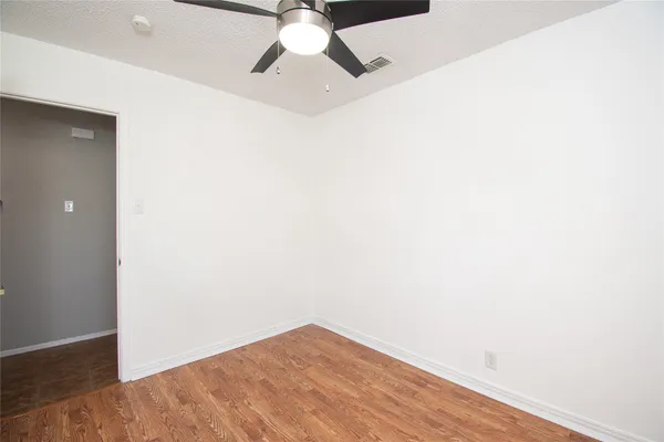 an empty room with a ceiling fan and wooden floor
