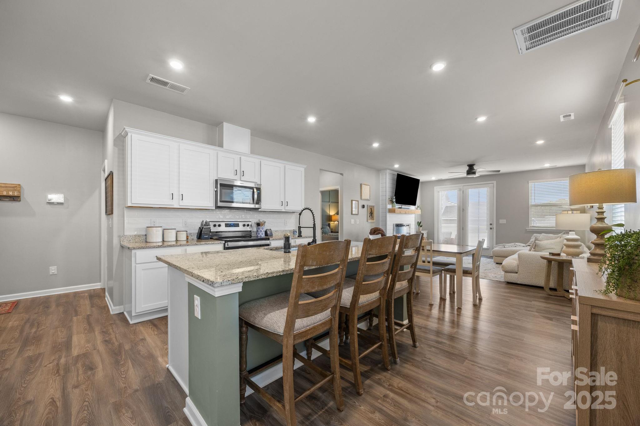 567 Sitka Drive York, SC 29745 - Photo 8 of 40 a kitchen with a dining table chairs wooden floor stainless steel appliances and cabinets
