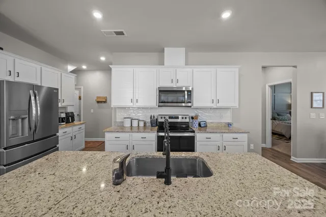 a kitchen with stainless steel appliances granite countertop a table chairs sink refrigerator and cabinets