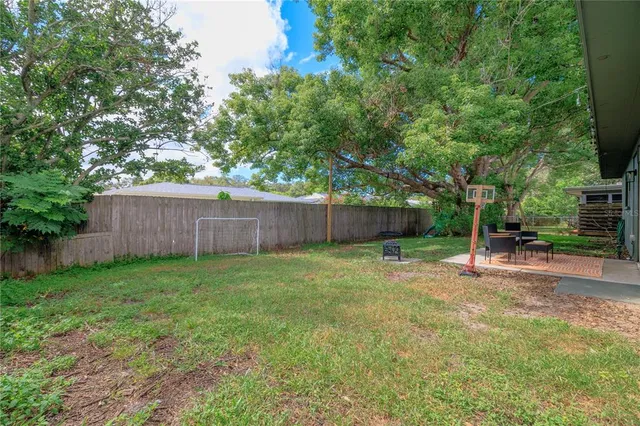 a view of a backyard with large trees and wooden fence