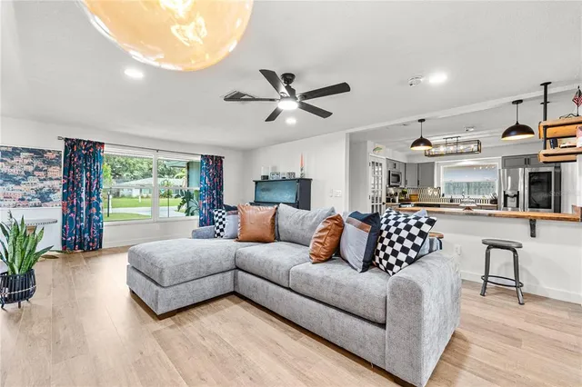 a living room with furniture ceiling fan and a large window