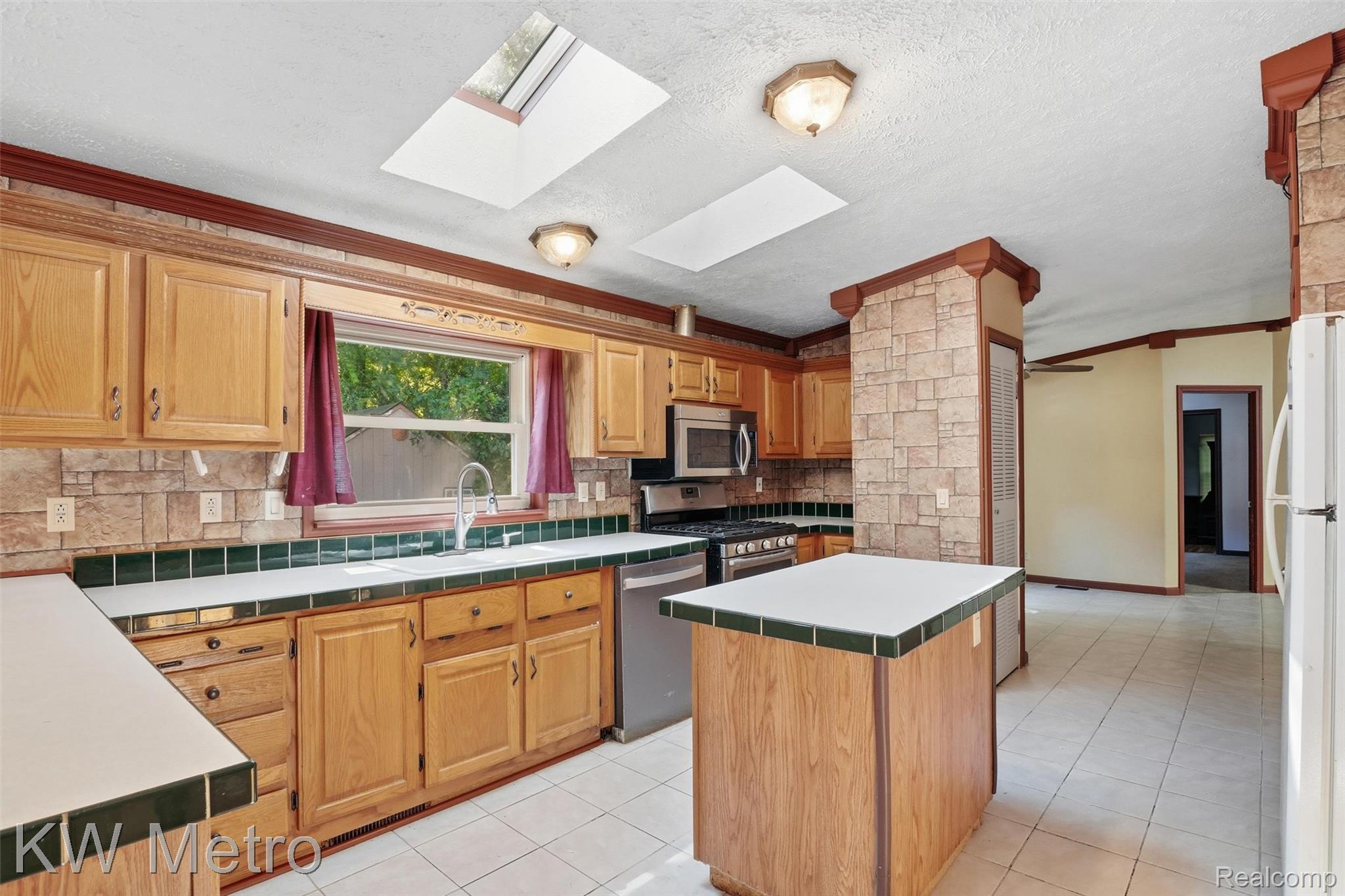 22733 Sumpter Road Belleville, MI 48111 - Photo 19 of 52 Kitchen featuring wood cabinetry, a central island with countertop, and an integrated stainless steel dishwasher and range
