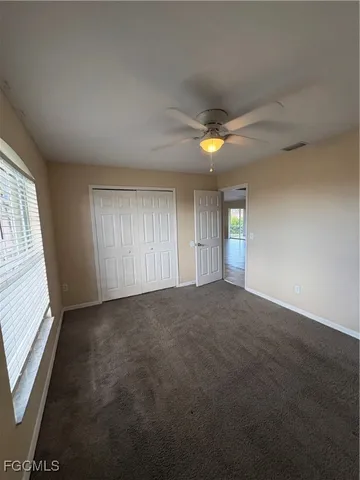 an empty room with windows and chandelier fan