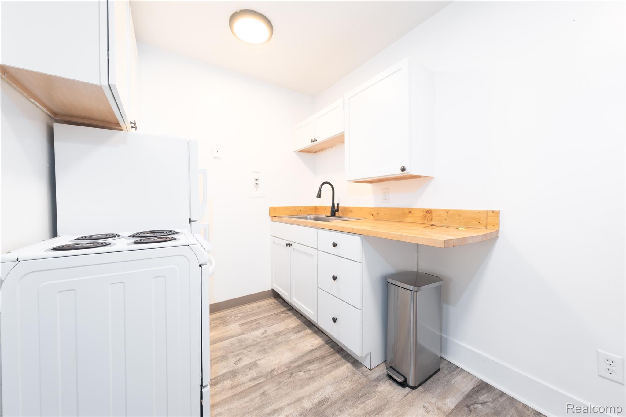 3065 South Commerce Road, Unit 11 Walled Lake, MI 48390 - Photo 6 of 12 Galley kitchen with wood-finish flooring, white cabinetry, wood countertops, and a black gooseneck faucet