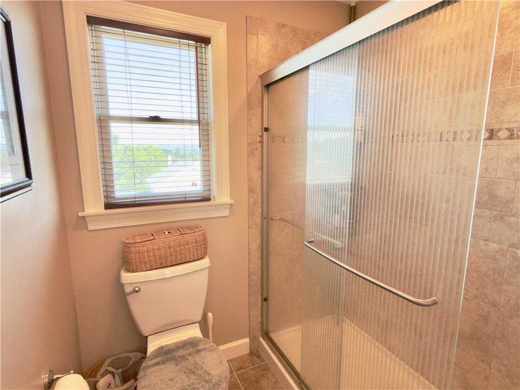 4982 Abbey Road Coplay, PA 18037 - Photo 33 of 55 Tiled walk-in shower with sliding glass doors stands adjacent to a classic sash window.