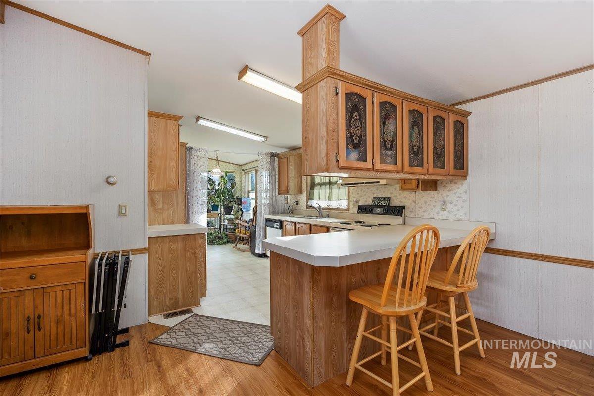 198 South Hills Road, Unit 142 Twin Falls, ID 83301 - Photo 11 of 27 Kitchen featuring a peninsula, a kitchen breakfast bar, glass insert cabinets, light countertops, and light wood finished floors